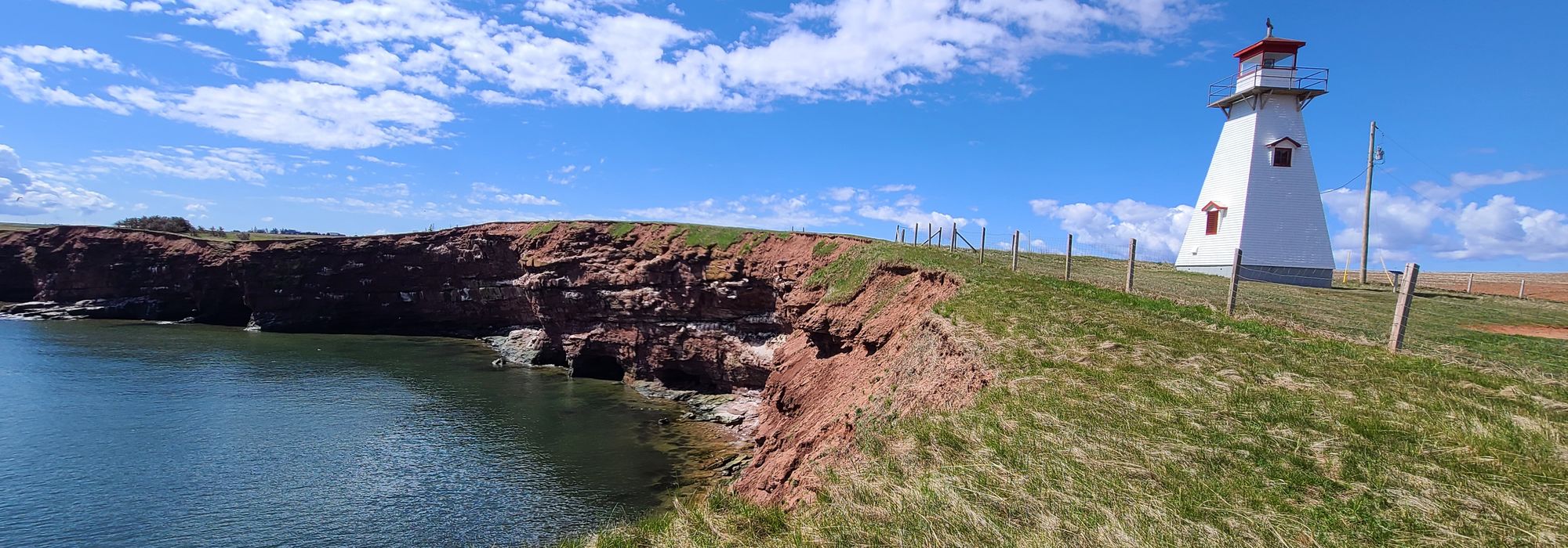 Red sandstone cliffs and a lighthouse above the water on Prince Edward Island